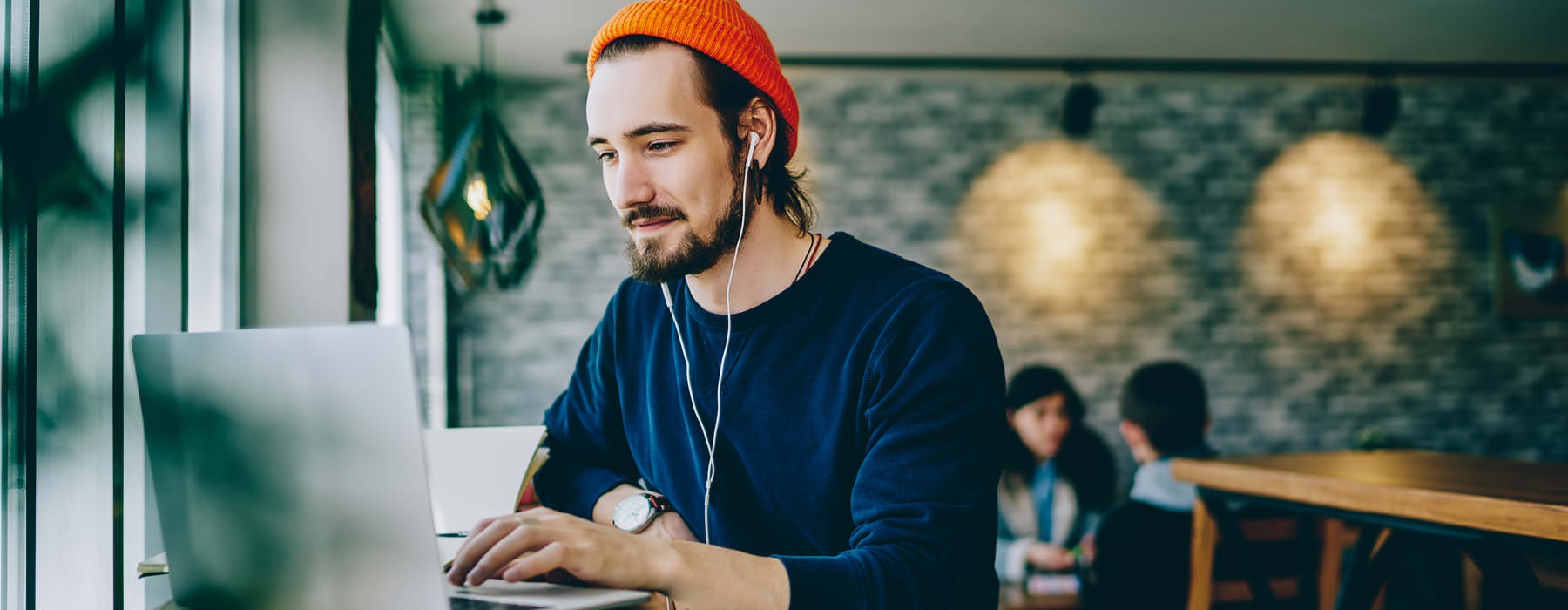 young man works on his laptop in nearby cafe